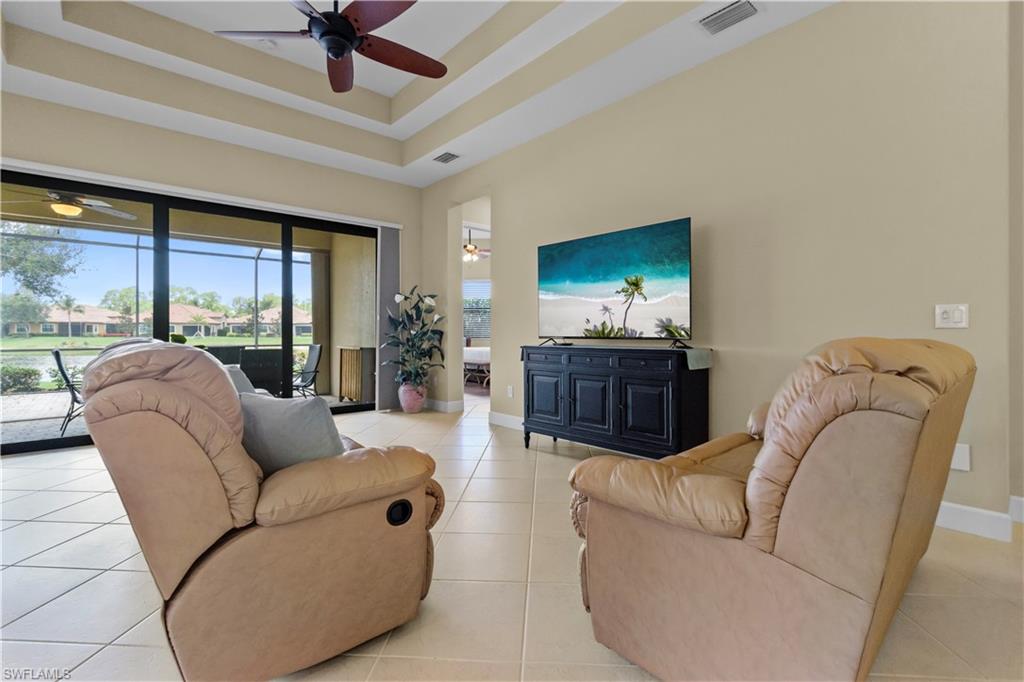 Living area with tray ceilings, ceiling fan, and large format tile flooring
