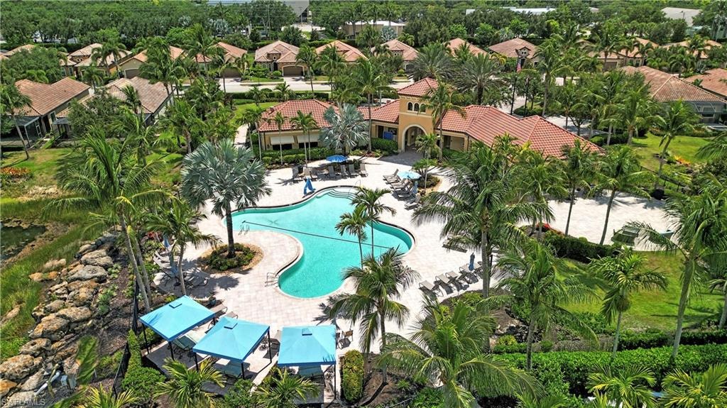 Resort-style pool area featuring a freeform swimming pool, extensive paved sundeck, and multiple shaded cabanas