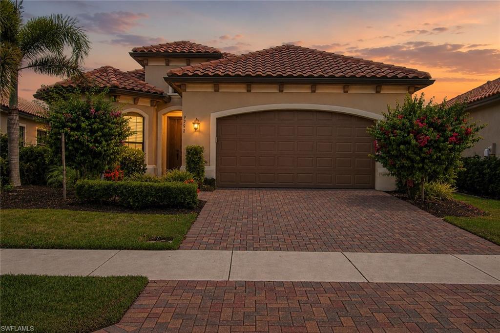 Mediterranean-inspired residence featuring a terracotta tile roof, stucco exterior, and a brick paver driveway