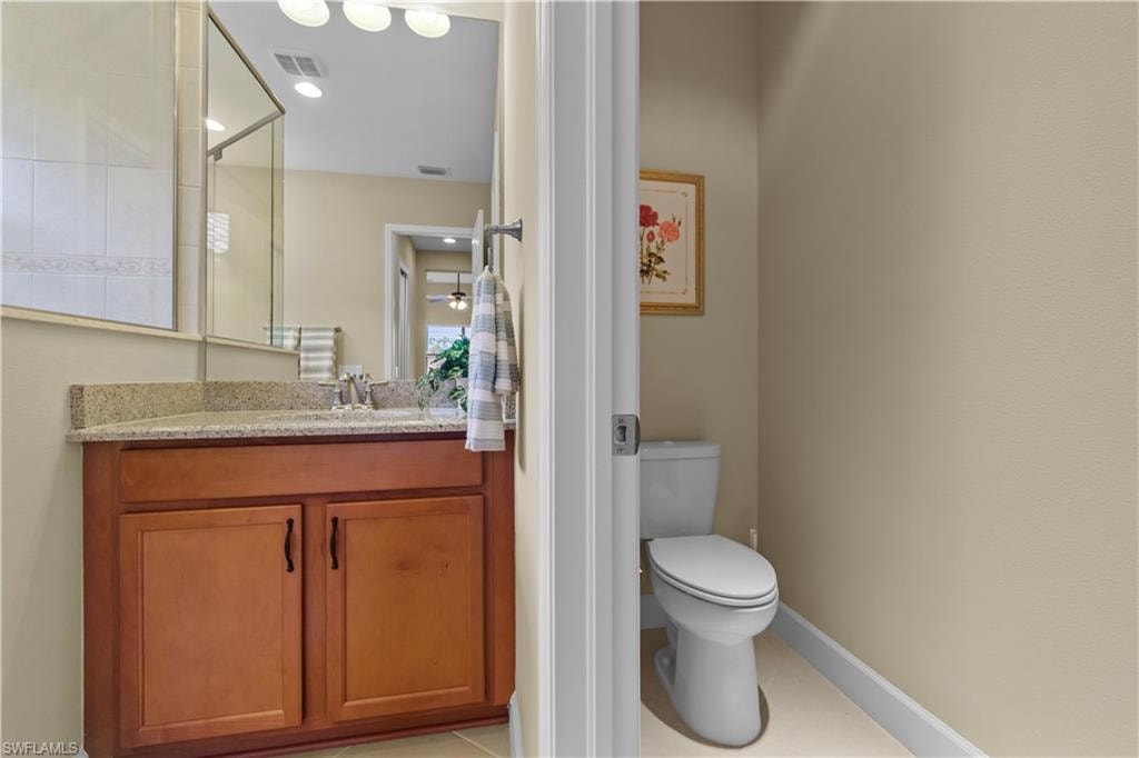 Bathroom featuring a wood-finish vanity with a speckled countertop, a mirrored vanity, and a glass-enclosed shower
