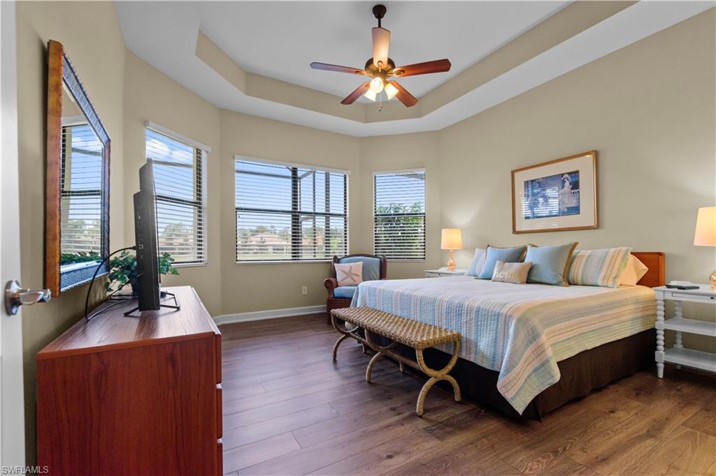 Spacious primary bedroom featuring wood-finish flooring, a tray ceiling, and beautiful water views.