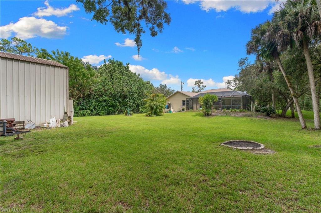 Expansive lawn space featuring mature perimeter trees and a dedicated fire pit area