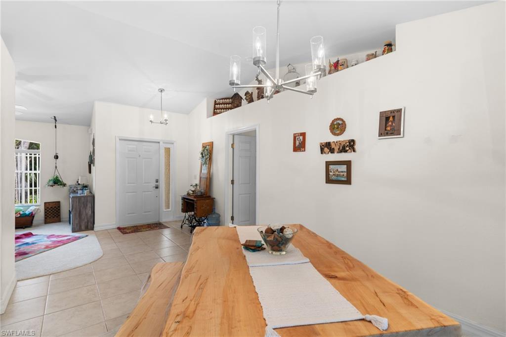 Open-concept dining area featuring a natural wood-finish dining table and a contemporary chandelier