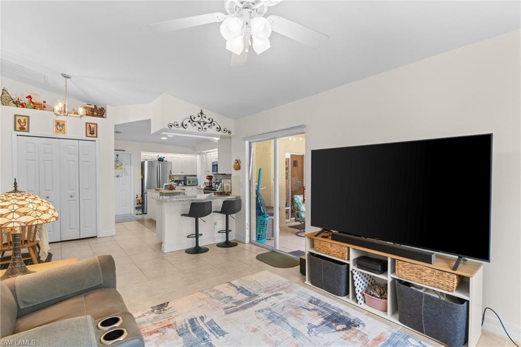 Open-concept living space featuring a kitchen with a breakfast bar, stainless steel appliances, and a pass-through to the living area