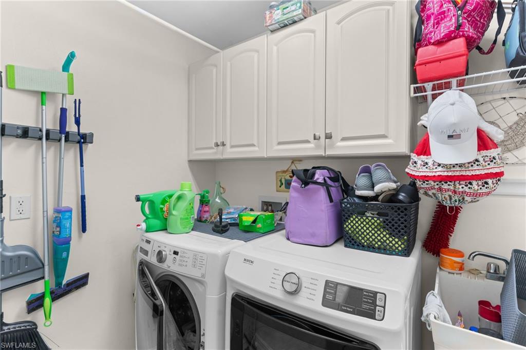 Dedicated laundry area featuring white upper cabinetry with brushed nickel hardware, a utility sink, and a wall-mounted storage rack