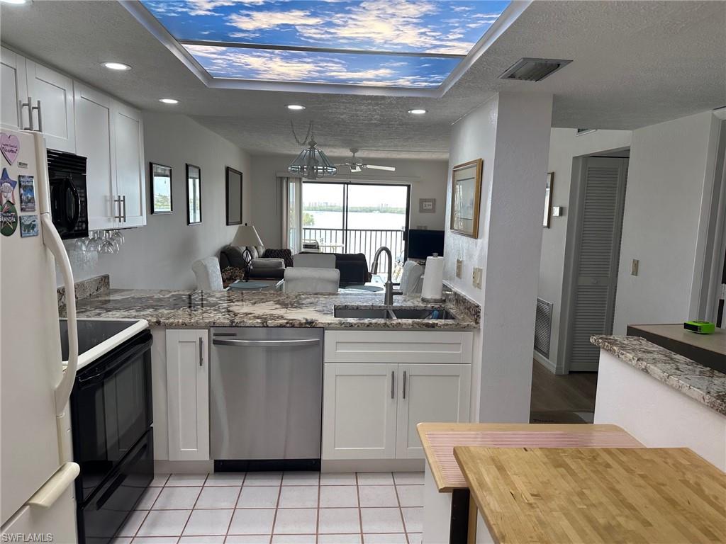 Kitchen featuring white shaker-style cabinetry, stainless steel appliances, granite countertops, and tile flooring