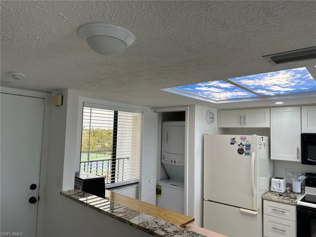 Kitchen area featuring white cabinetry, a granite-patterned countertop, and a sky-effect ceiling light panel