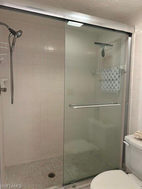 Glass-enclosed shower featuring a handheld showerhead and light-toned square tile walls