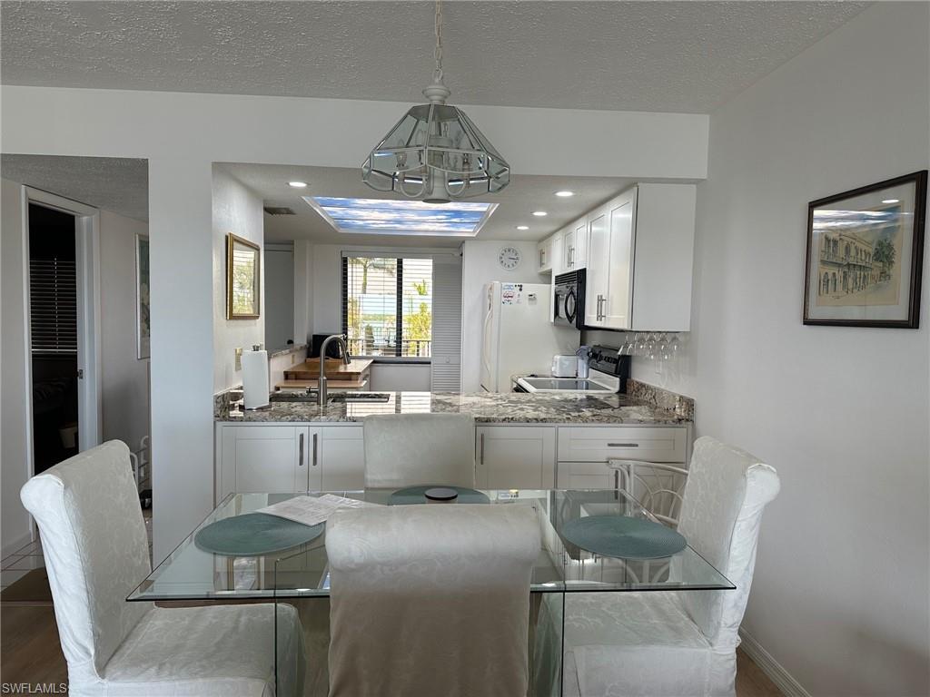 Open-concept kitchen featuring white cabinetry, granite-finish countertops, recessed lighting, and a skylight