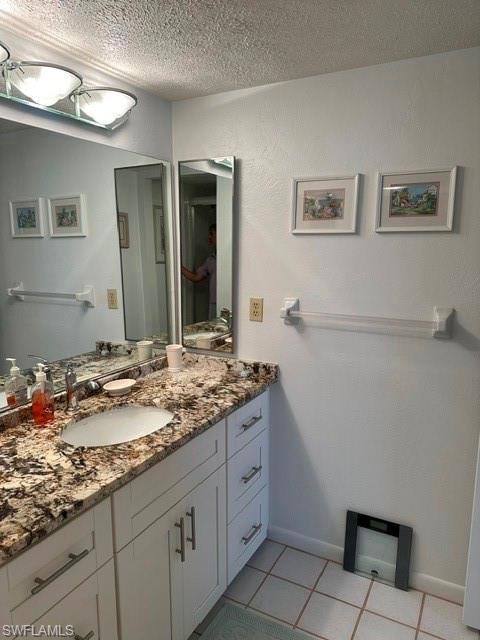 Bathroom vanity featuring an integrated sink, granite-style countertop, white cabinetry with brushed nickel hardware, and tile flooring