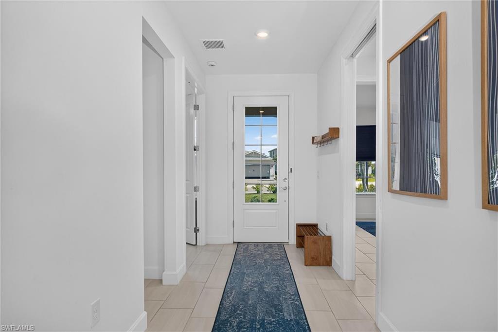 An inviting entryway with soaring ceilings, and a long hallway/foyer which creates a bright open feel while offering a beautiful sightline into the living room area and beyond