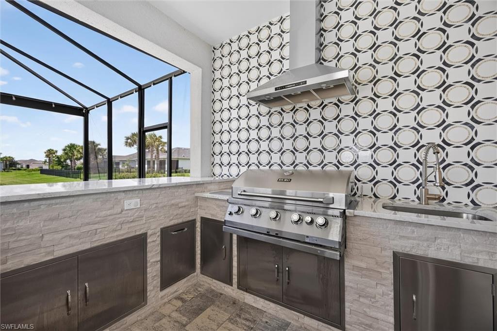 outdoor kitchen with gas grille, plenty of storage space an a wine cooler