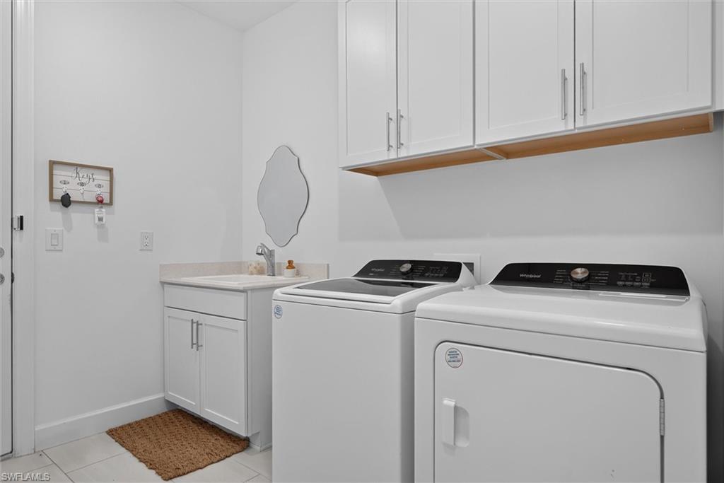 laundry room offers abundant upper cabinetry, a utility sink with a base cabinet and plenty of room for storage