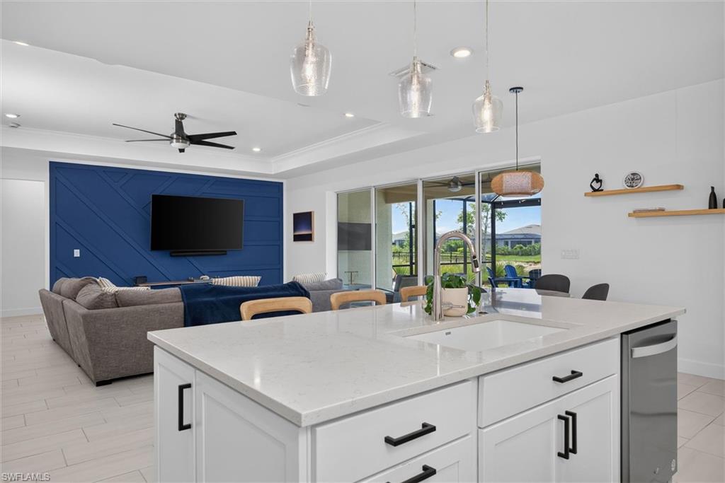 the kitchen is the heart of the home featuring a large quartz island with seating and designer pendant light and an open view to the great room and outdoor living space