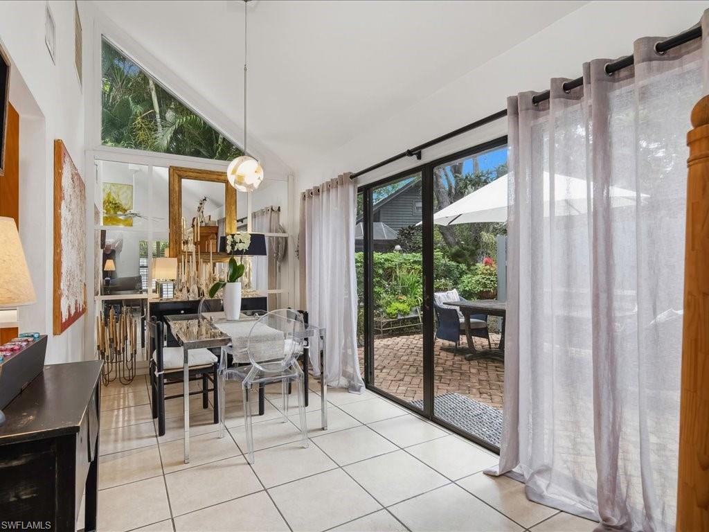 Dining area featuring vaulted ceilings, a prominent triangular transom window, and tile flooring