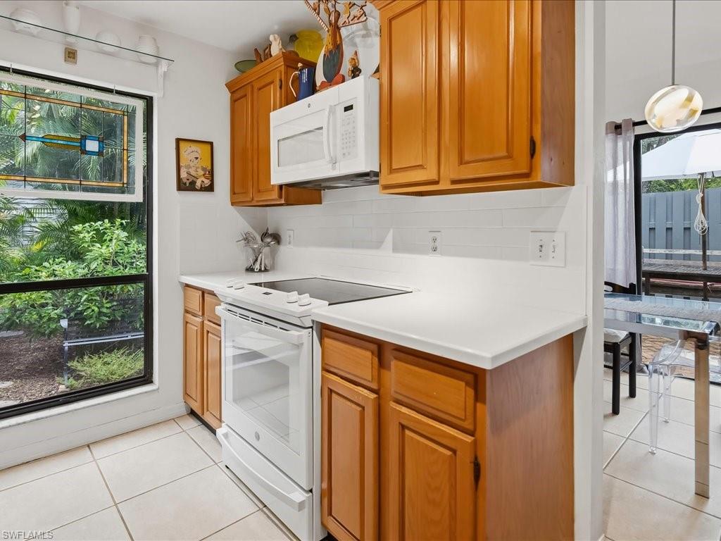 Kitchen featuring wood cabinetry, white countertops, white subway tile backsplash, and a white electric range with a microwave above