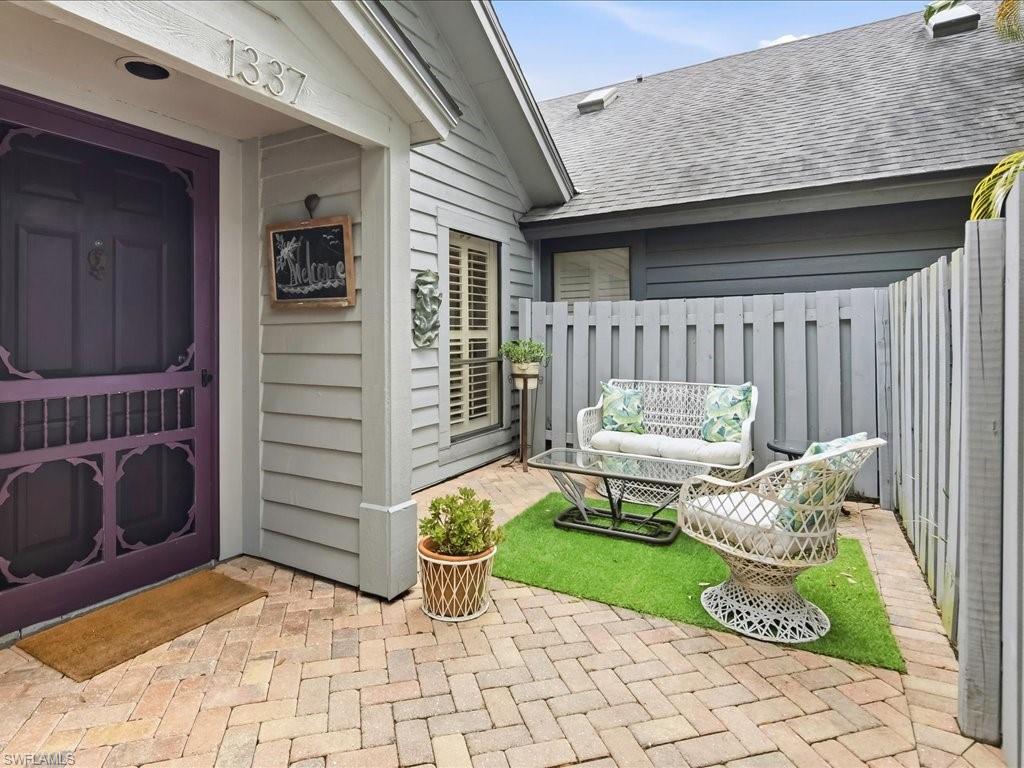 Private courtyard entry featuring herringbone brick pavers and a decorative purple screen door