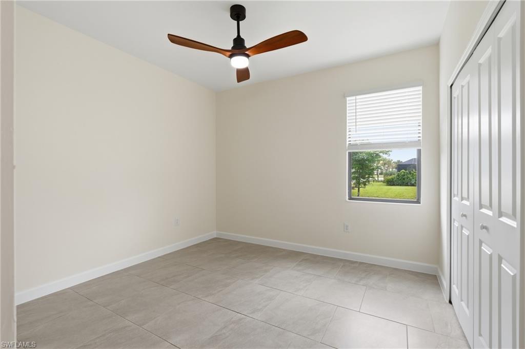 Neutral-toned room featuring large format tile flooring and a ceiling fan with integrated lighting