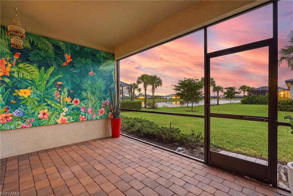Screened lanai featuring brick paver flooring, a vibrant mural wall, and a tropical hanging light fixture