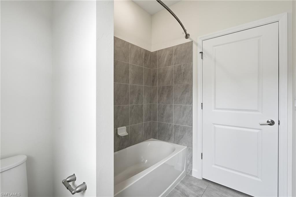 Bathroom featuring a white bathtub, gray tile surround, and coordinating gray tile flooring