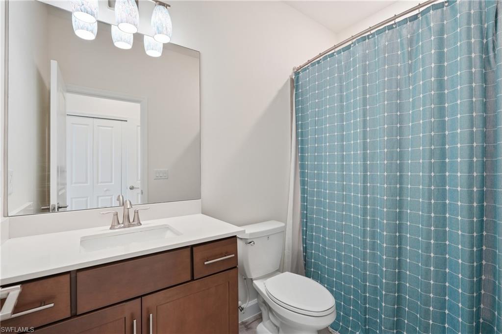 Bathroom featuring a wood-finish vanity with a white countertop, undermount sink, and a large mirror
