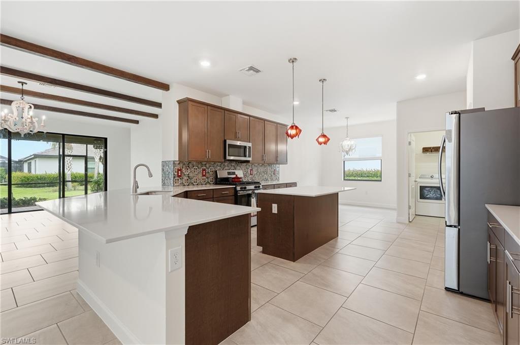 Kitchen featuring white countertops, a mosaic tile backsplash, stainless steel appliances, and wood-finish cabinetry