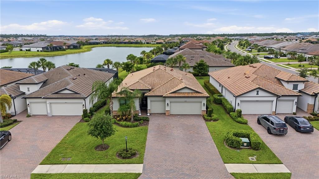 Mediterranean-style residence featuring a tile roof, paved driveway, mature landscaping, and a three-car garage