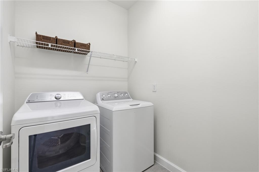Dedicated laundry area featuring a wire storage shelf, light gray wall paint, and white baseboards