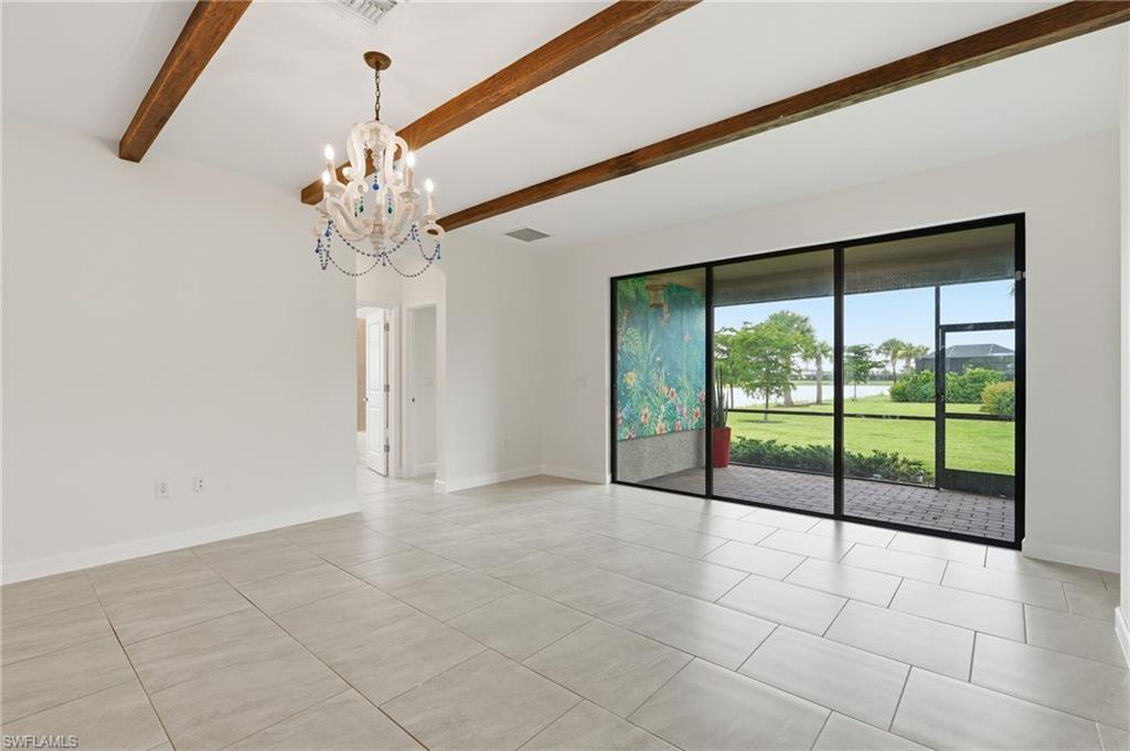 Spacious interior featuring a large sliding glass door, exposed wood beams, and a decorative chandelier