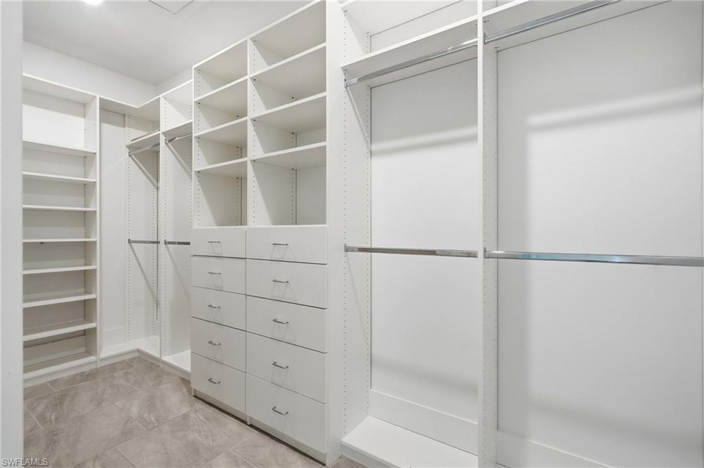Built-in closet system featuring white shelving, multiple hanging rods, and integrated drawers with contemporary hardware