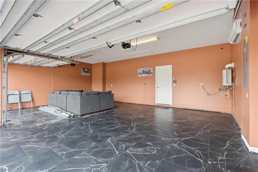 Spacious garage featuring dark, veined tile flooring, a white interior door, and a wall-mounted water heater