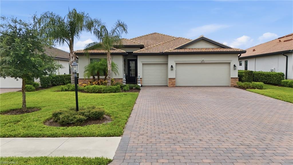 Single-story residence featuring a tile roof, stucco exterior, and a paver driveway