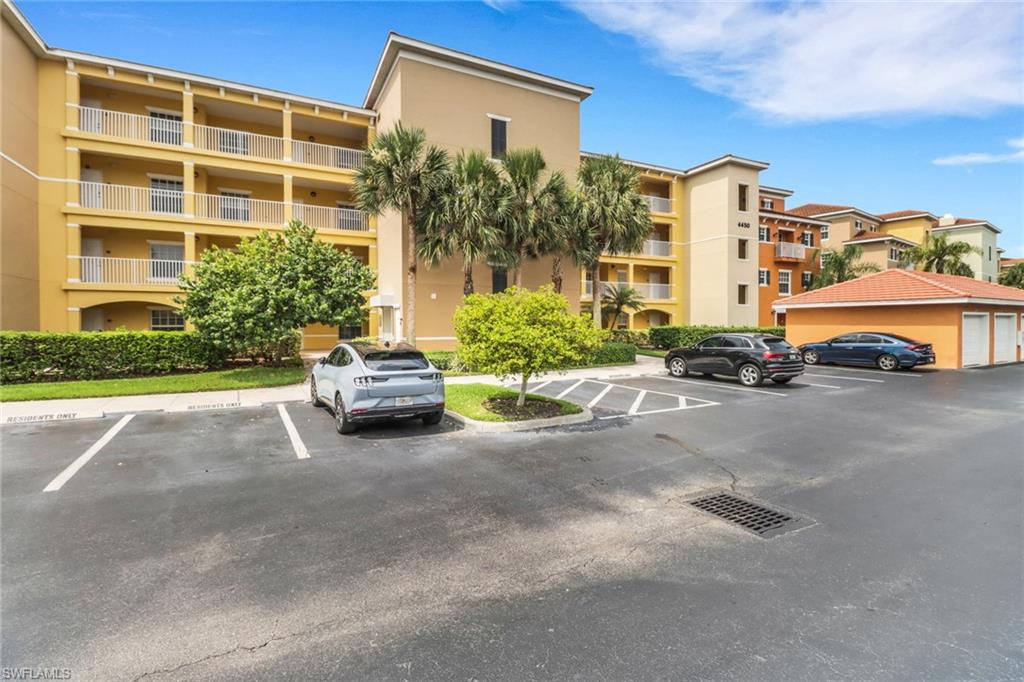 View of apartment building / complex featuring uncovered parking
