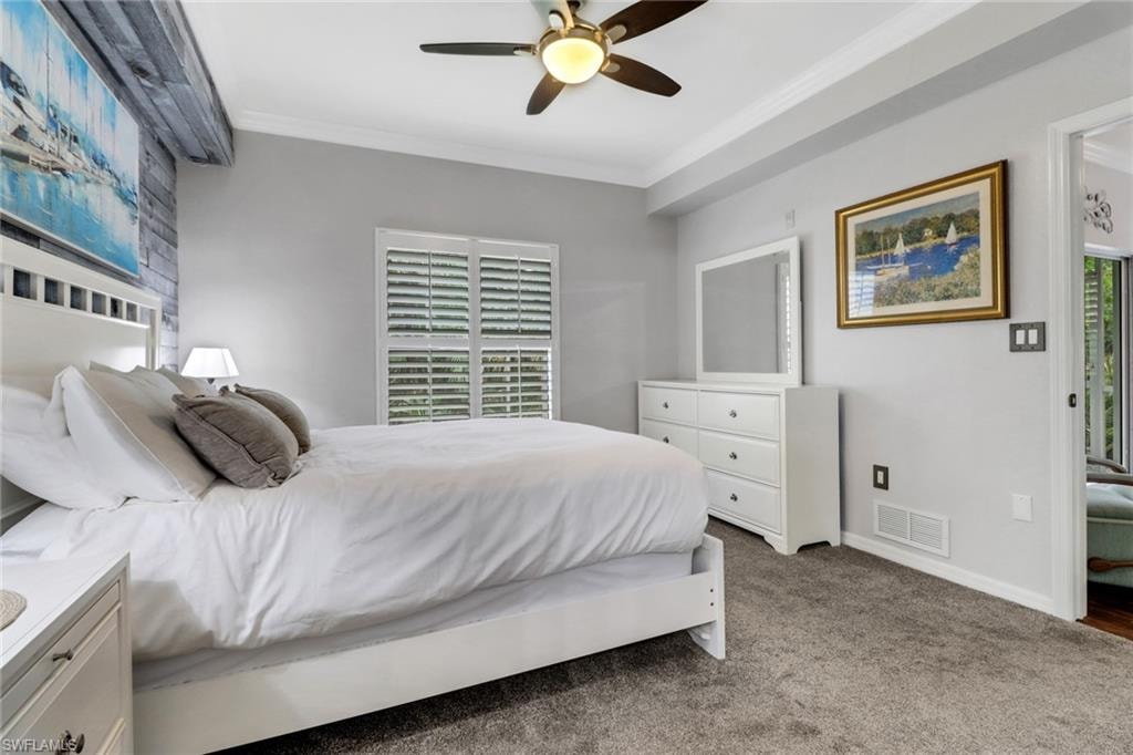 Carpeted bedroom featuring ornamental molding, ceiling fan, and baseboards