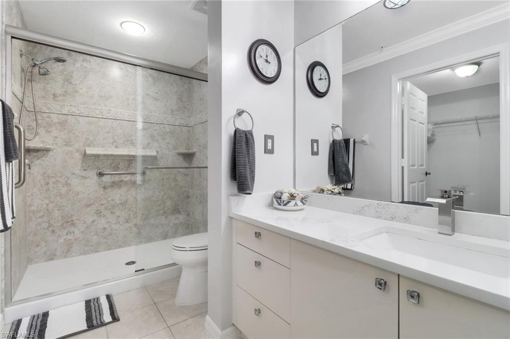 Full bathroom with toilet, a shower stall, tile patterned flooring, vanity, and ornamental molding