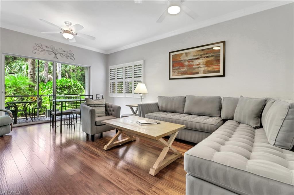 Living room with a ceiling fan, wood finished floors, and crown molding