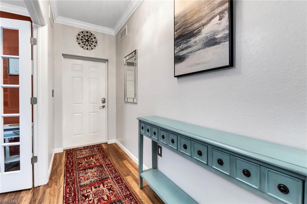Doorway to outside featuring ornamental molding, wood finished floors, and baseboards