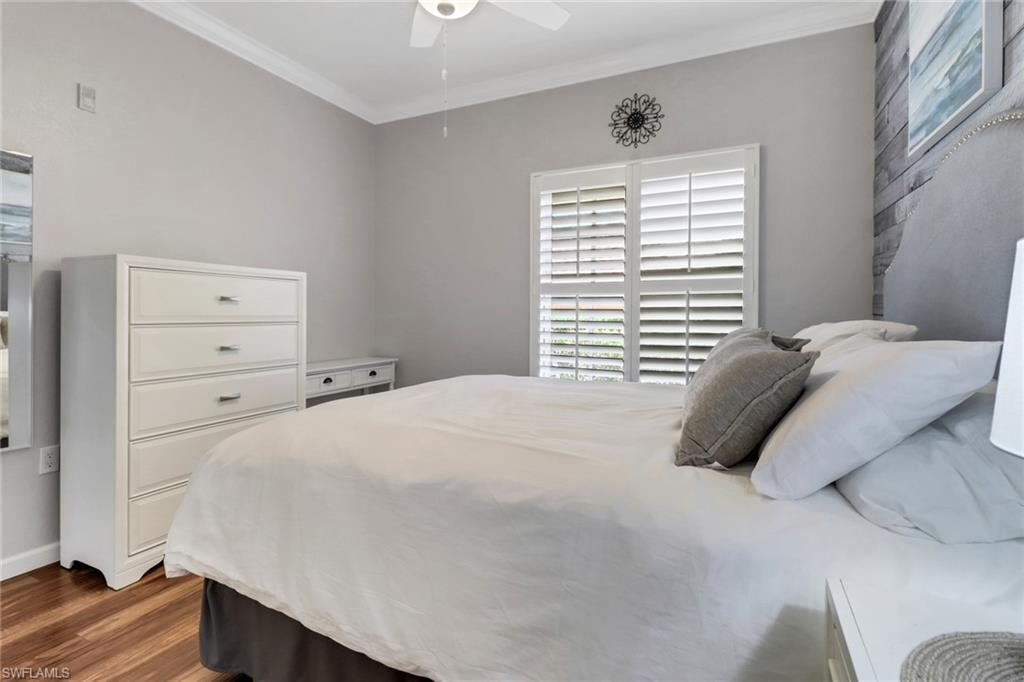 Bedroom with ornamental molding, wood finished floors, and ceiling fan