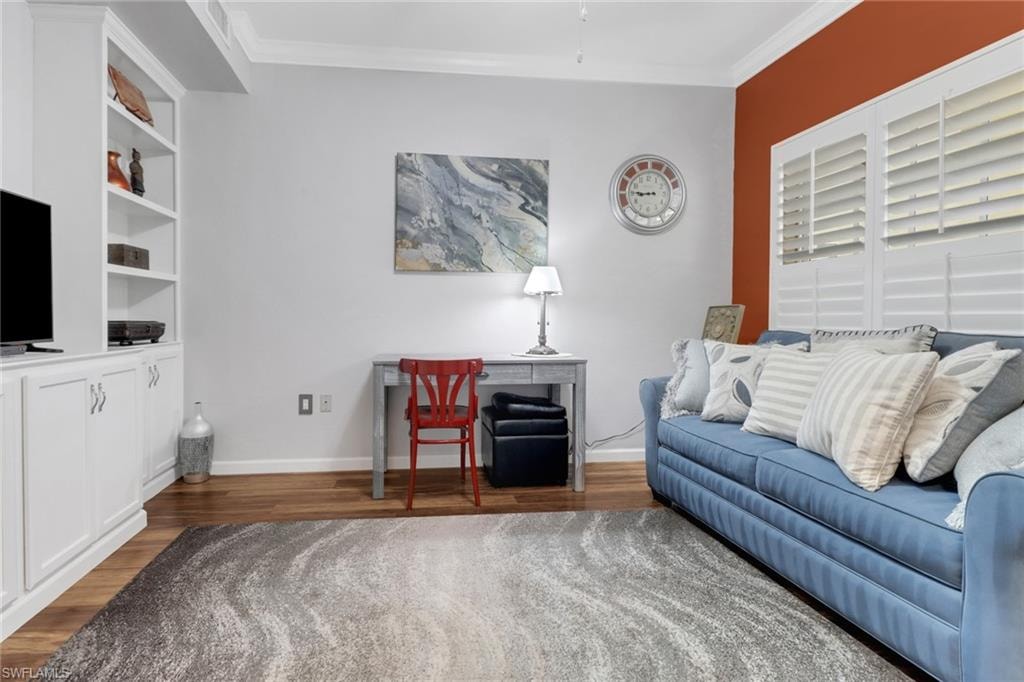 Living room featuring wood finished floors, ornamental molding, and baseboards
