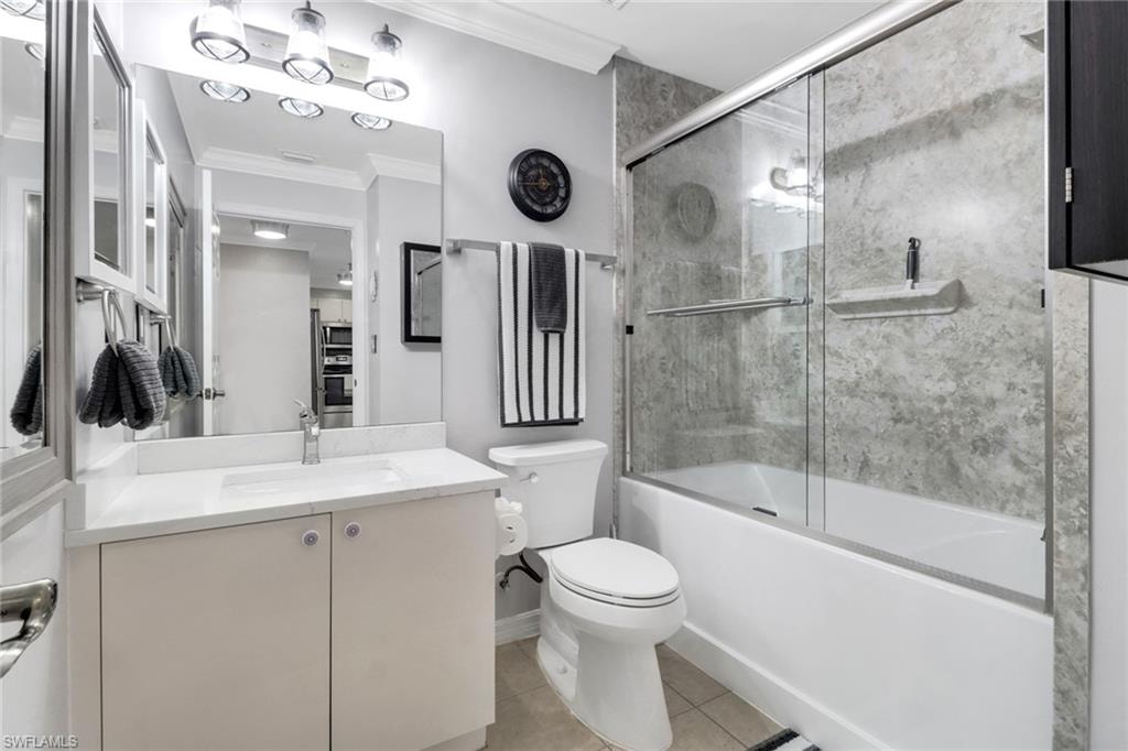 Full bath with crown molding, toilet, vanity, tile patterned floors, and enclosed tub / shower combo