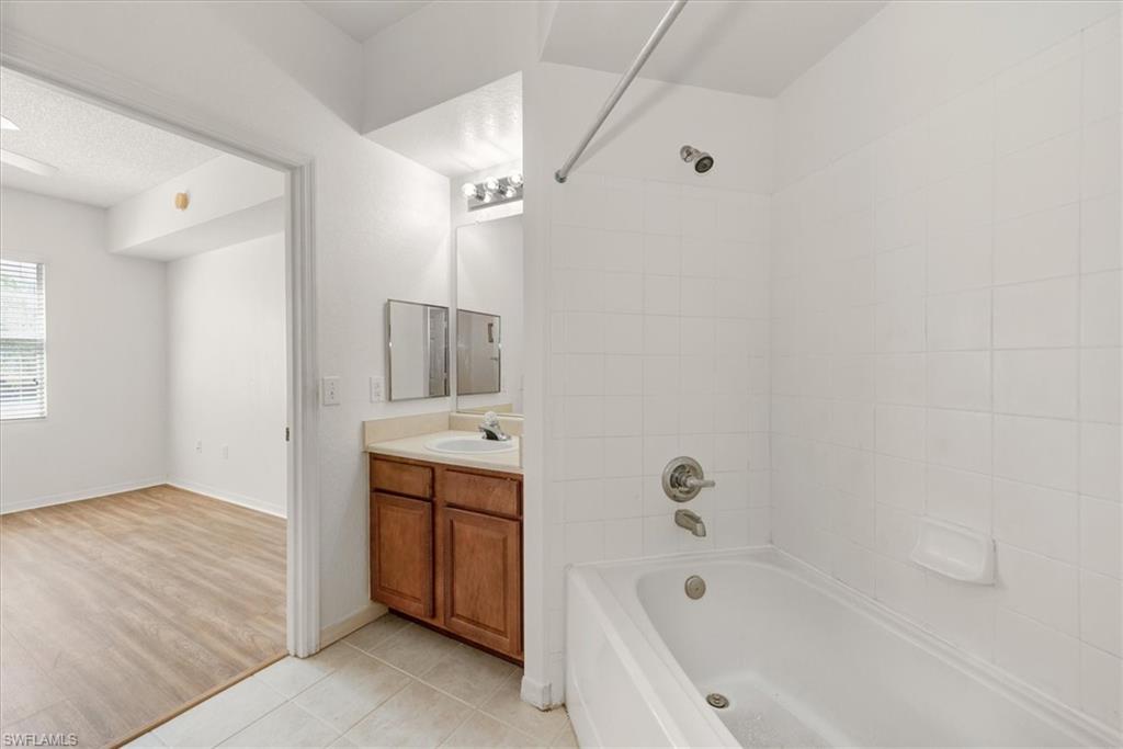 Bathroom featuring a full-size bathtub with shower combination, white tiled walls, and brushed nickel fixtures