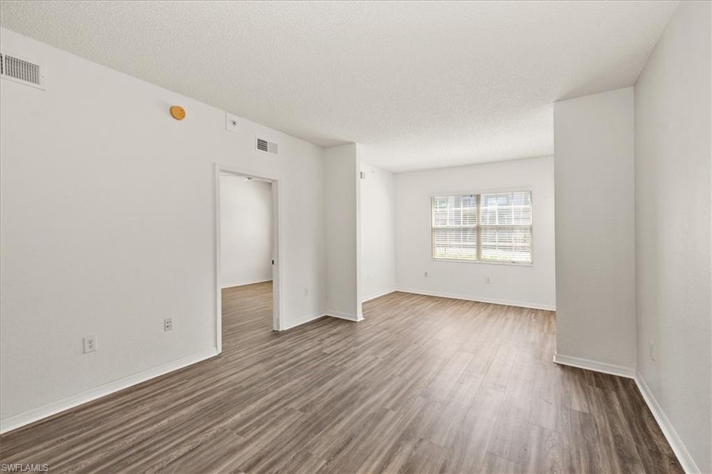 Spacious room featuring wood-finish flooring, white baseboards, and a large window