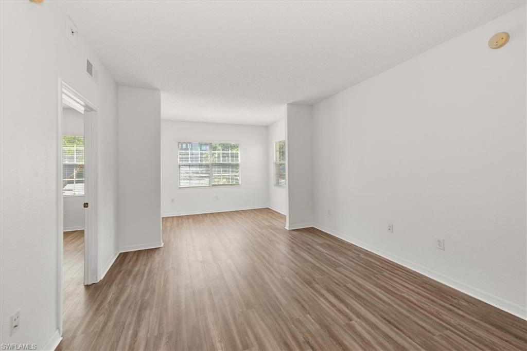 Spacious interior featuring wood-finish flooring, white walls, and multiple windows