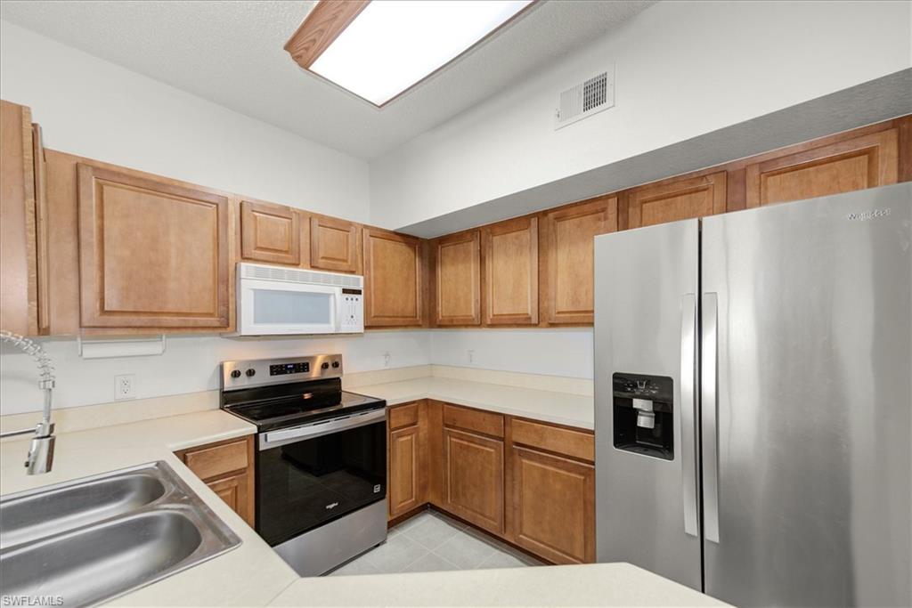 Kitchen featuring wood-finish cabinetry, light-toned countertops, and stainless steel appliances