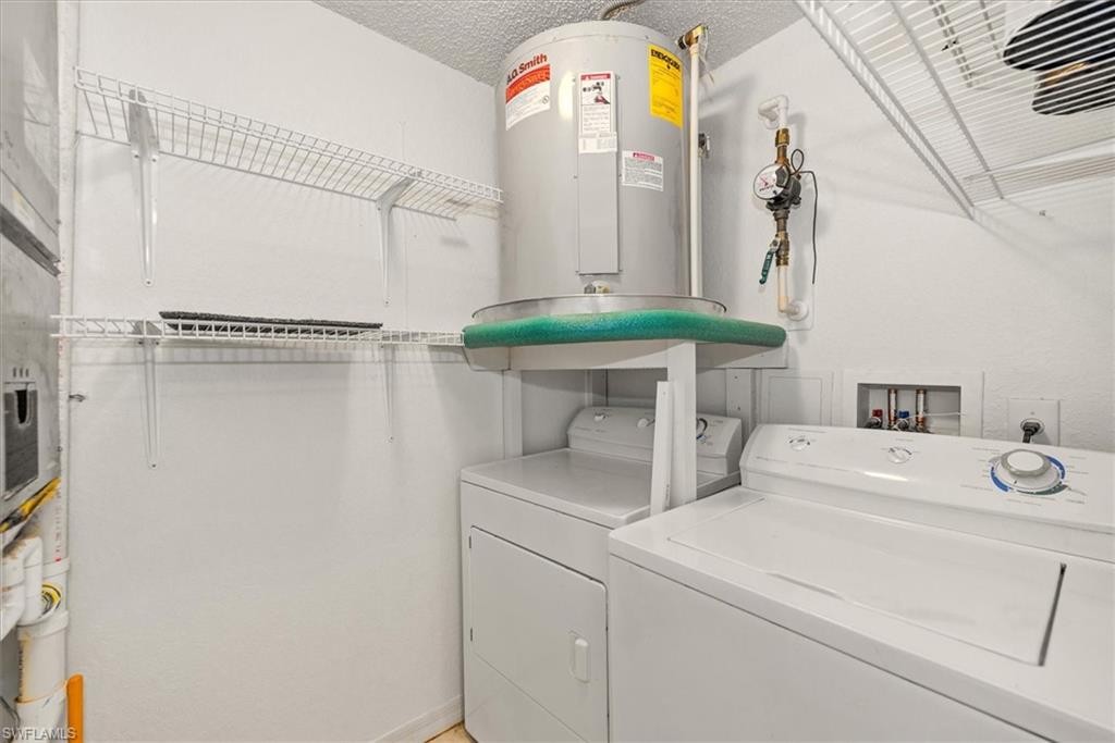 Dedicated utility space featuring a washer and dryer, a water heater, and overhead wire shelving