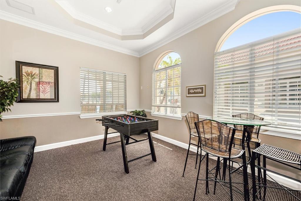 Room featuring Foosball table, arched windows, tray ceiling with recessed lighting, crown molding, and two-tone wall paint