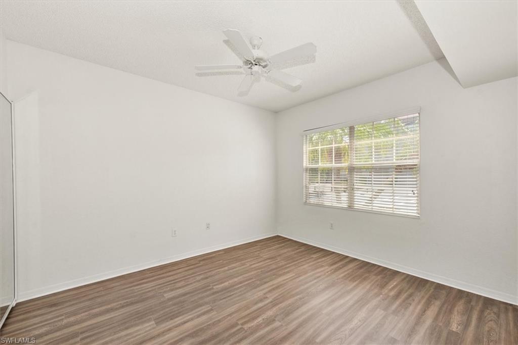 Bright room with wood-finish flooring, a window featuring blinds, a ceiling fan, and white walls