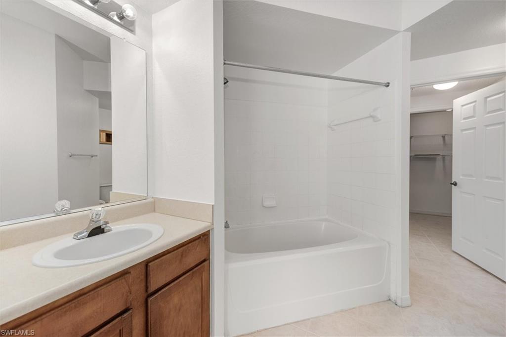Bathroom vanity with wood-finish cabinetry, a light-toned countertop, and an integrated white sink