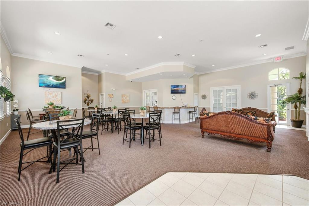 Clubhouse II - Spacious common area featuring textured carpeting, a multi-stool bar, and multiple round tables with chairs