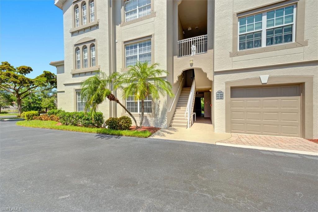 Multi-story building exterior featuring a neutral stucco finish, decorative arched windows, and an integrated garage with a neutral-toned door